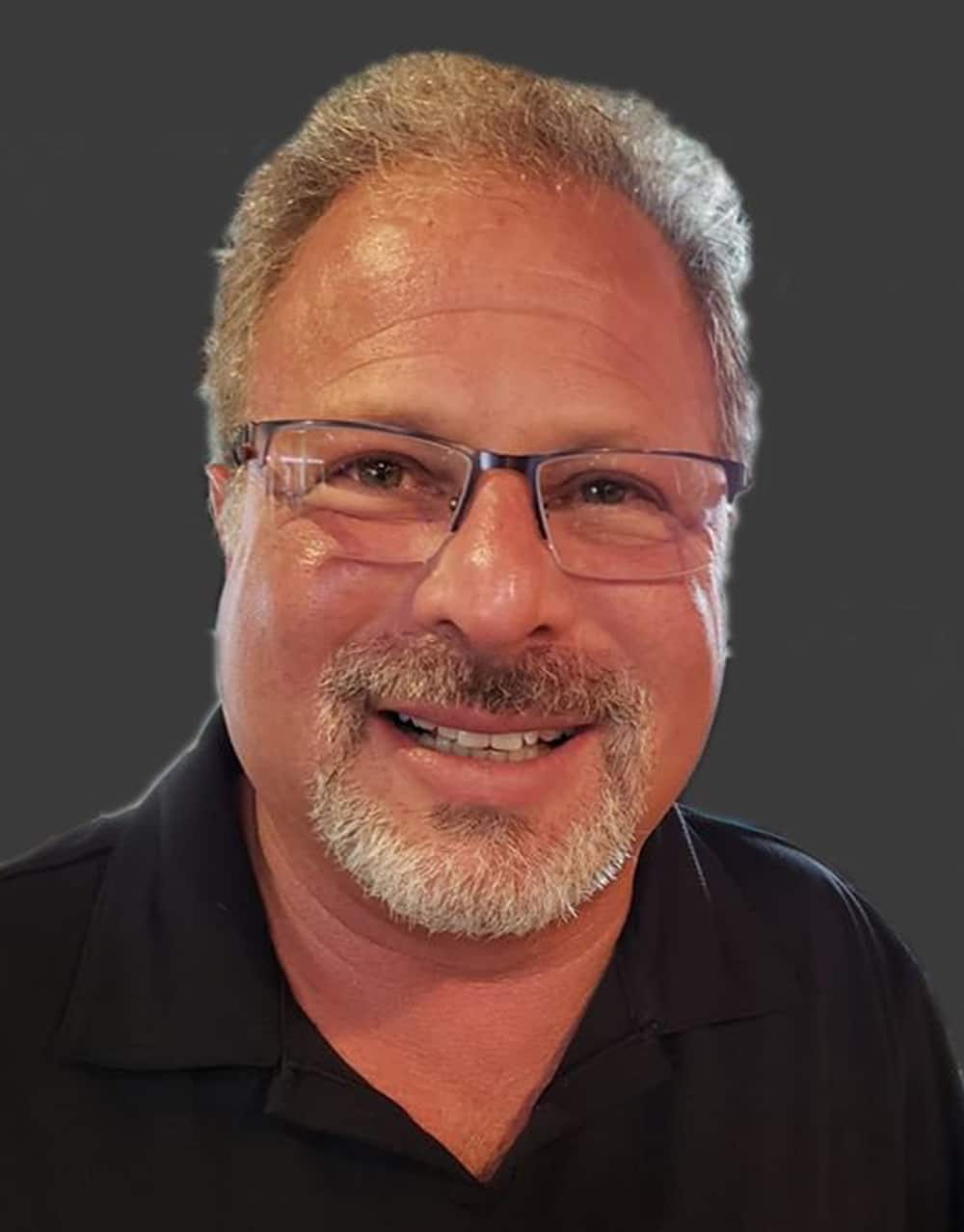 a man wearing glasses and smiling at the camera